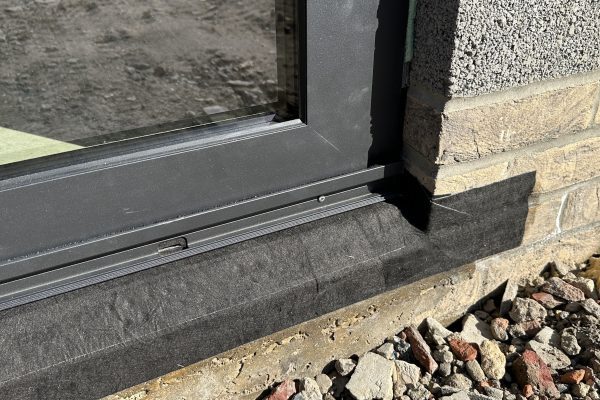Close-up of aluminium sliding door threshold with airtight membrane detailing and thermal break, part of a bespoke exterior glazing and interiors installation.